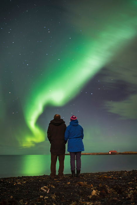 Couple watching the Northern Lights (Aurora Borealis), Reykjavik, Iceland